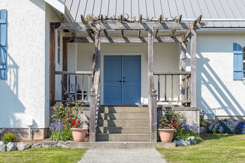 Blue front door and covered entrance of the renovated 1937 farmhouse at Emandare Winery